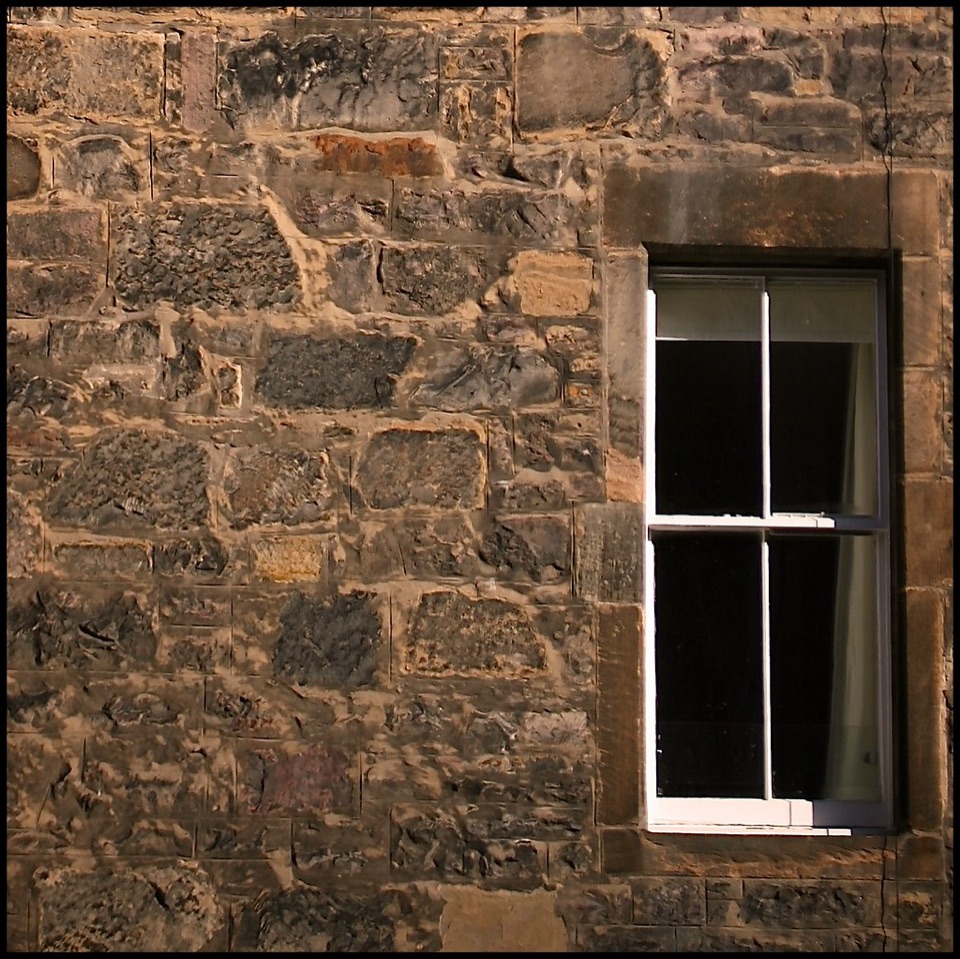 A rubble sandstone wall with a dressed stone window surround in Edinburgh